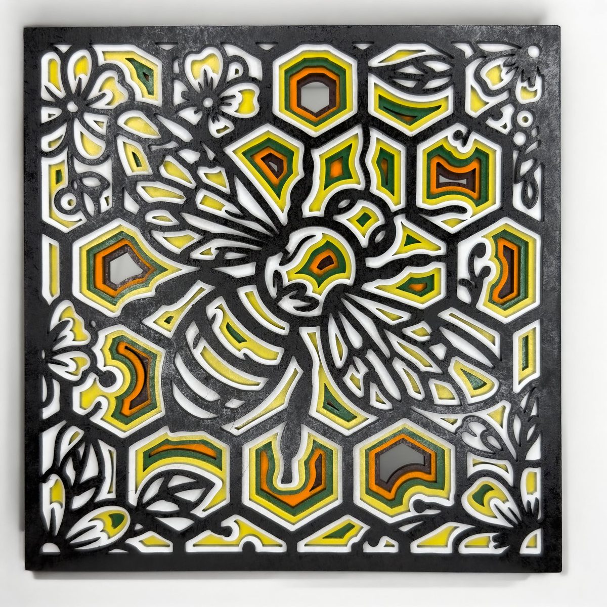 The same butterfly and honeycomb design with a black top layer over yellow, orange and green painted layers.