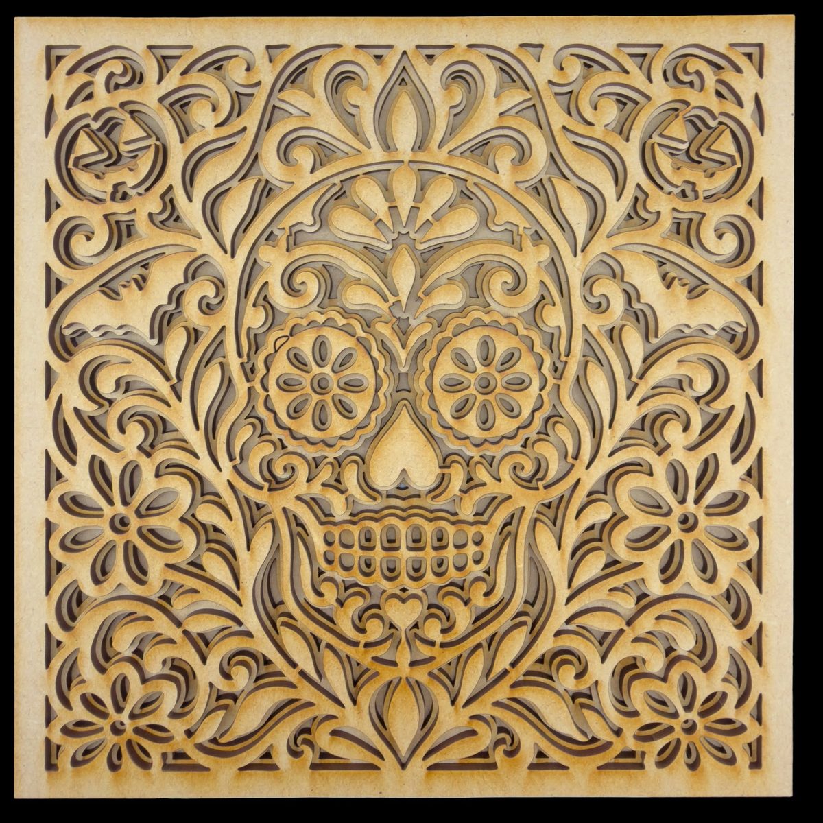 A square layered panel in pale birch: a sugar skull at the centre surrounded by dense symmetrical flower and scroll work, inside a plain border.