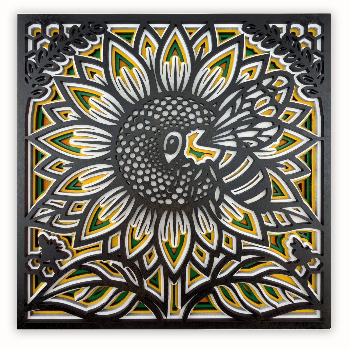 The same sunflower design painted: a black top layer over yellow, green and white layers, with the seed head picked out in grey.